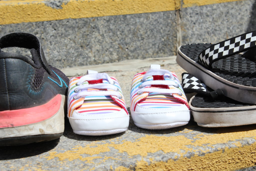 Brightly coloured stripes children's shoes on a concrete step.
