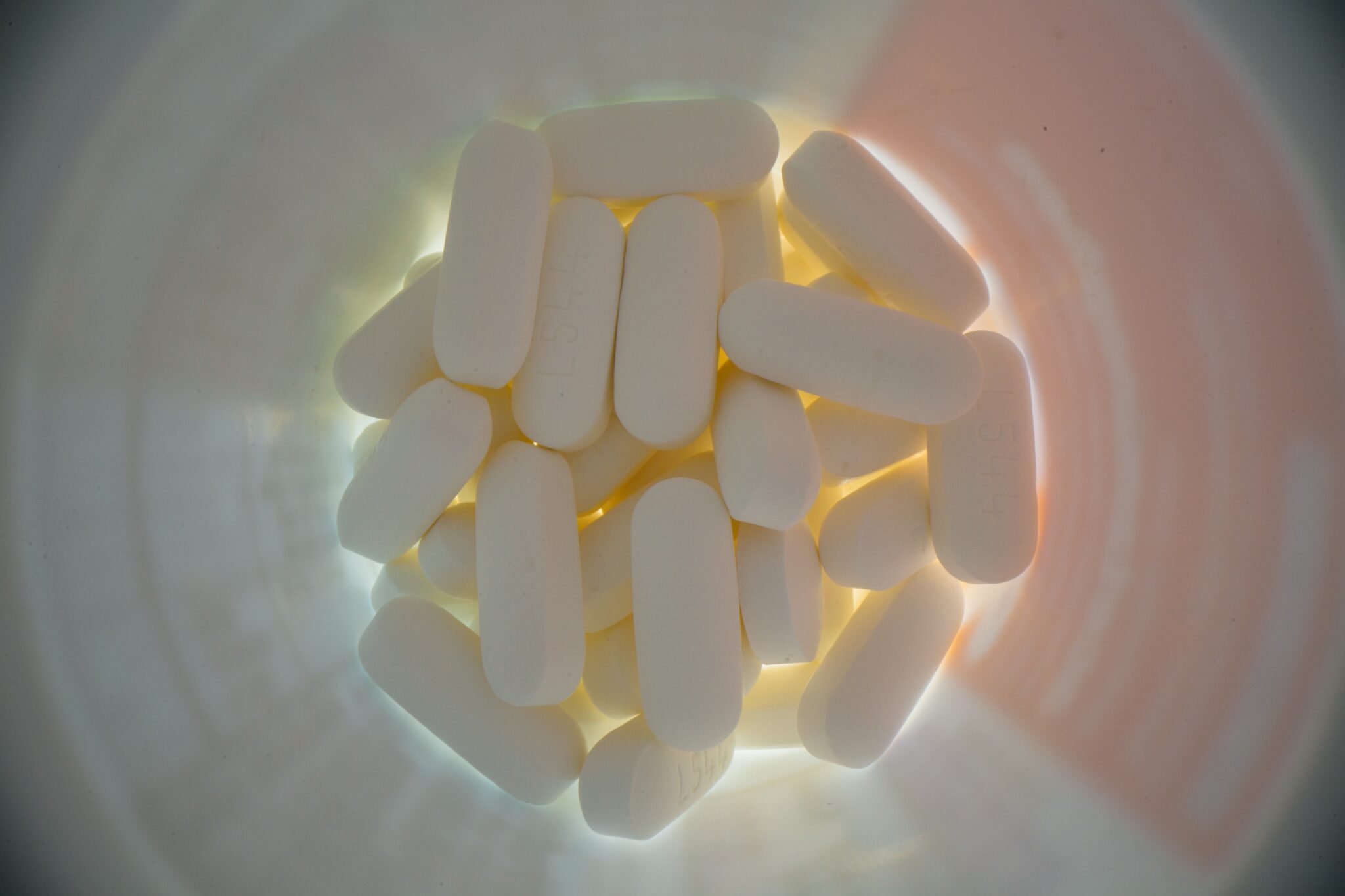 A photo of white pills in a bottle.